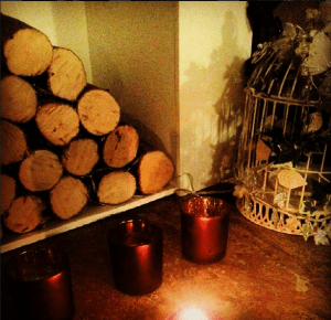 Wooden logs, candles and a birdcage creating hygge in the home