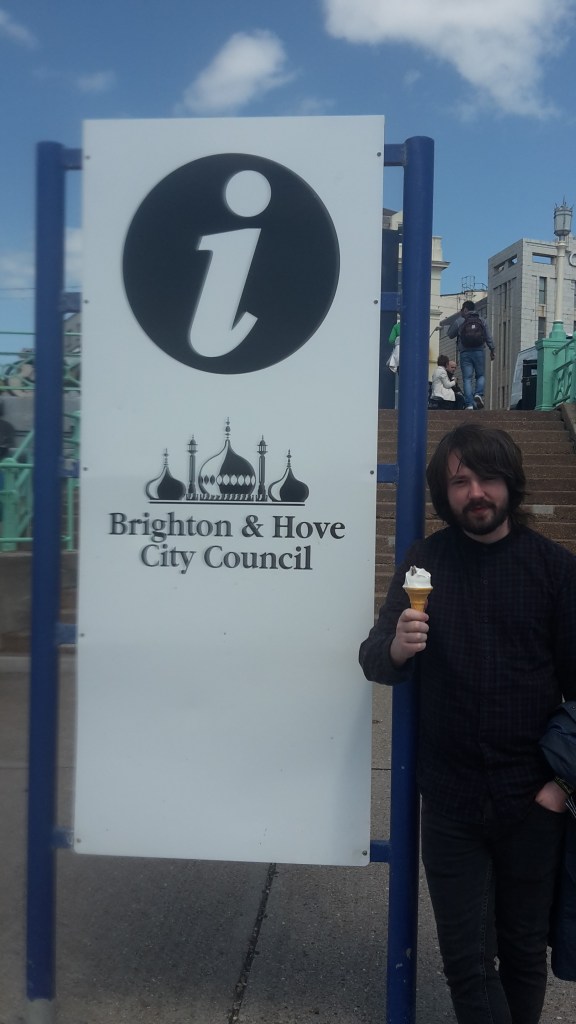 Dan eating ice cream standing next to Brighton & Hove City Council sign