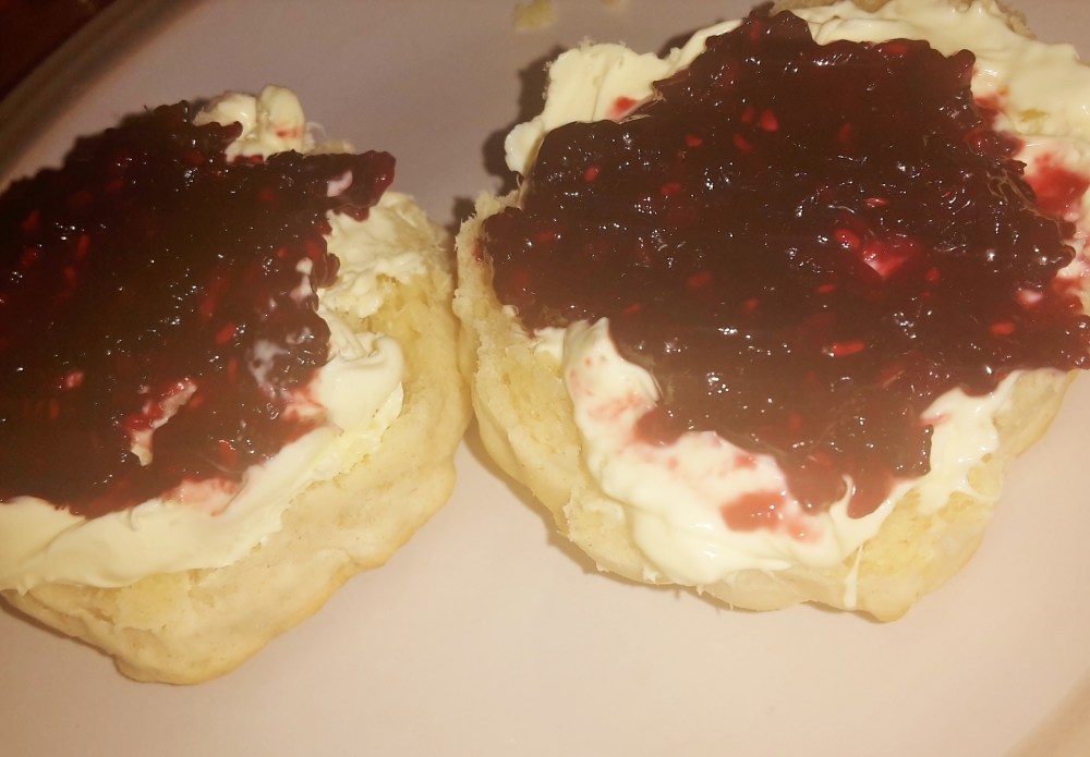 Scones topped with clotted cream and homemade blackberry and raspberry jam