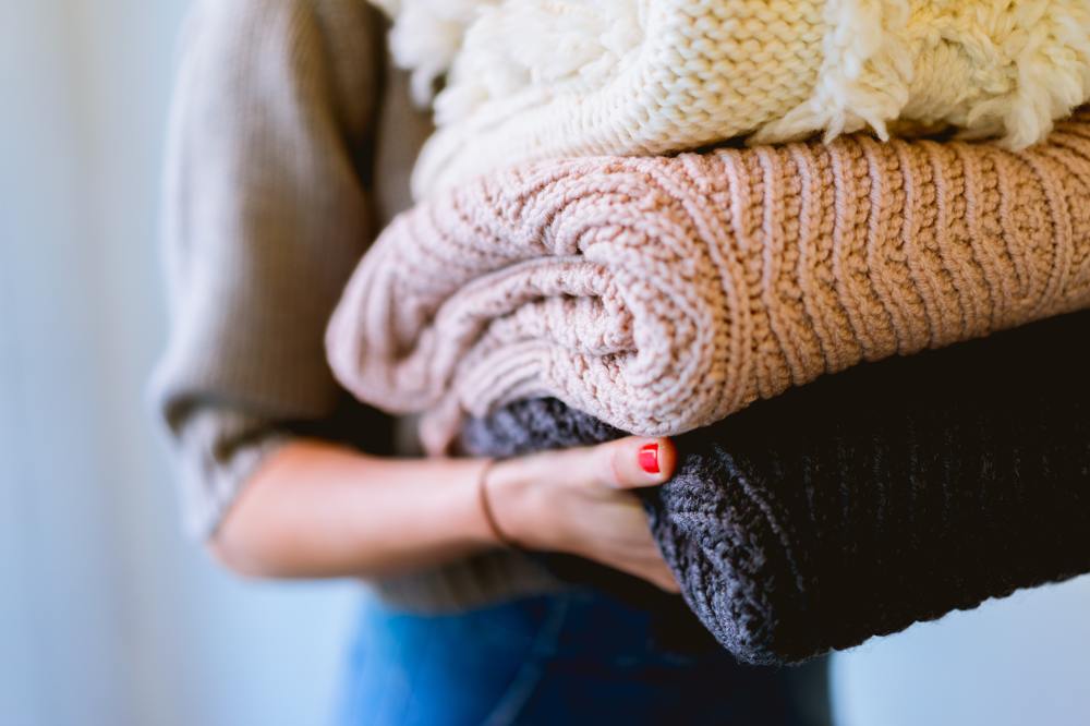 Woman carrying three woolly blankets